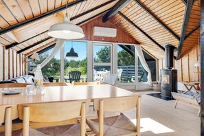 Um interior em madeira com uma mesa de jantar, cadeiras, um sofá e uma lareira.