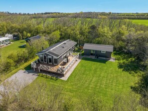 A modern house with a deck, a separate building, and a well-maintained lawn. - Lovely holiday home with annex and wilderness bath. (Vestervig)