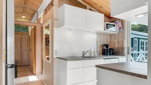 A modern kitchen with white cabinets, a stainless steel sink, and a microwave. - Lovely holiday home with annex and wilderness bath. (Vestervig)