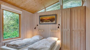 A wooden-paneled room with a bed, a painting, and a window. - Lovely holiday home with annex and wilderness bath. (Vestervig)