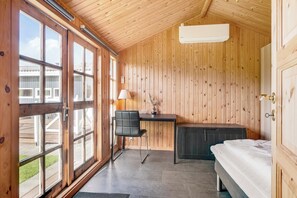 Une pièce aux murs lambrés, avec un lit, un bureau et une chaise.
