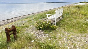 Een witte bank aan een meer, met een roestig object in de buurt.