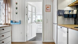 Een keuken met witte kastjes, een houten aanrecht en een klok aan de muur.