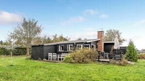 Ein Haus mit Veranda, Schornstein und kleinem Garten.