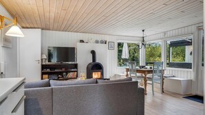 Ein Wohnzimmer mit Kamin, Sofa, Fernseher und Essbereich.