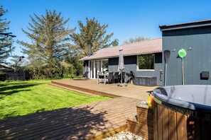 A backyard with a hot tub, wooden deck, and outdoor furniture. - Family-friendly holiday home with large wilderness bath, close to the water. (Vestervig)