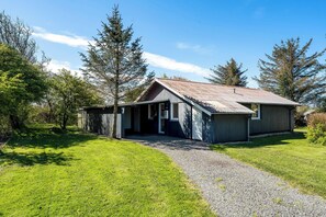 A single-story building with a gravel driveway leading to a wooden door. - Family-friendly holiday home with large wilderness bath, close to the water. (Vestervig)
