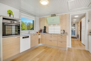 A modern kitchen with a built-in oven, a coffee machine, and a large window. - Family-friendly holiday home with large wilderness bath, close to the water. (Vestervig)