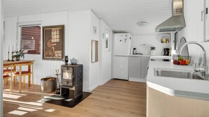 Une cuisine moderne dotée d’un poêle à bois, de meubles blancs et d’un évier.