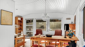 Un espace repas avec une table en bois, des chaises à coussins rouges et un luminaire suspendu.