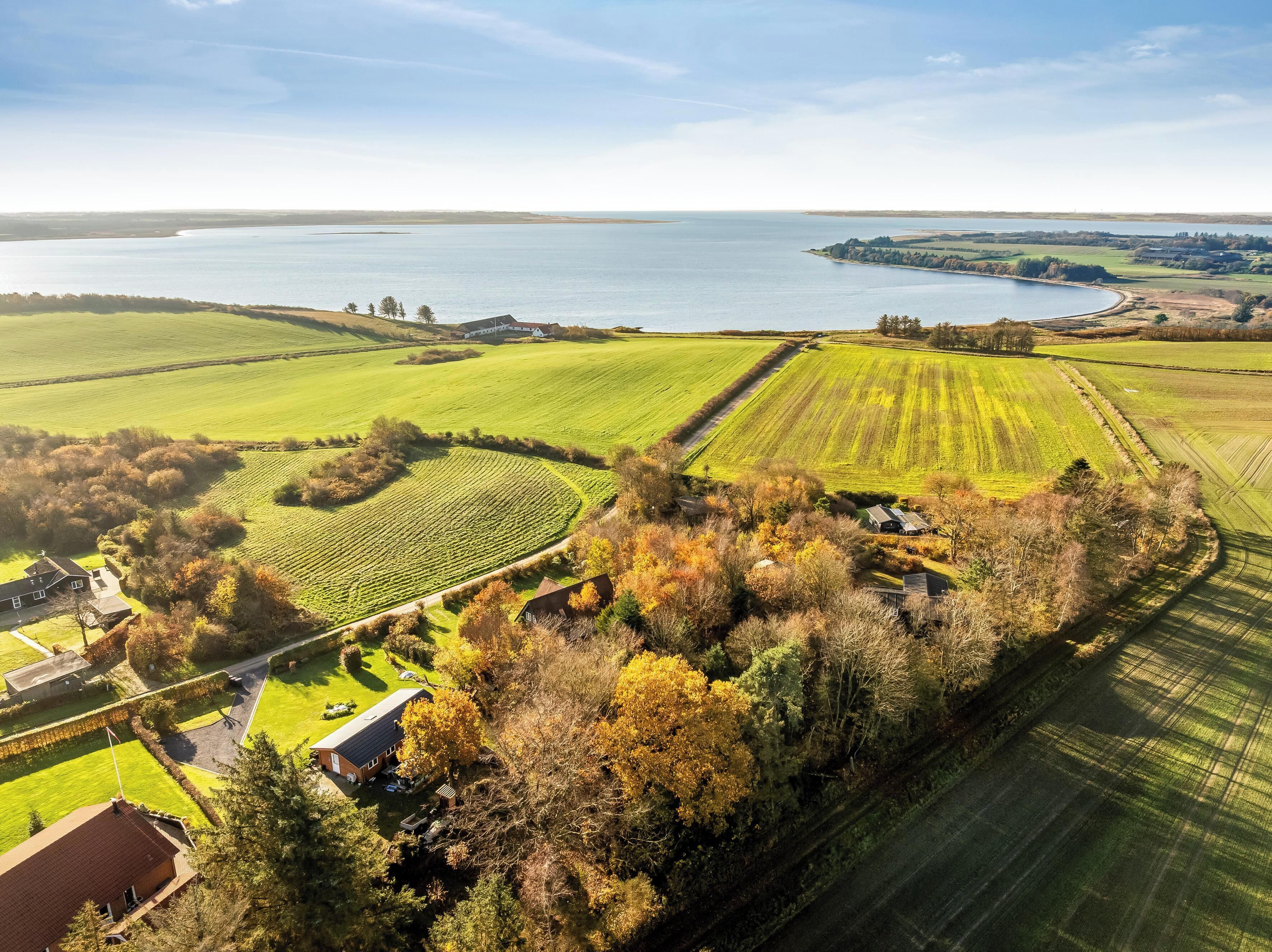 A rural landscape with fields, a body of water, and scattered buildings.