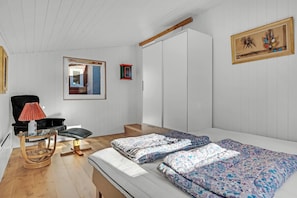 Une pièce comprenant un lit, une chaise, une petite table, un miroir et une armoire.
