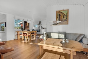 Une cuisine moderne avec des meubles blancs, un coin repas doté d’une table et de chaises en bois, et une grande fenêtre qui laisse entrer la lumière naturelle.