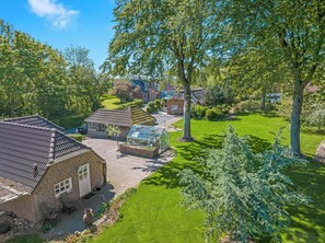 Una zona residencial con una casa de ladrillo, un invernadero y un césped bien cuidado.