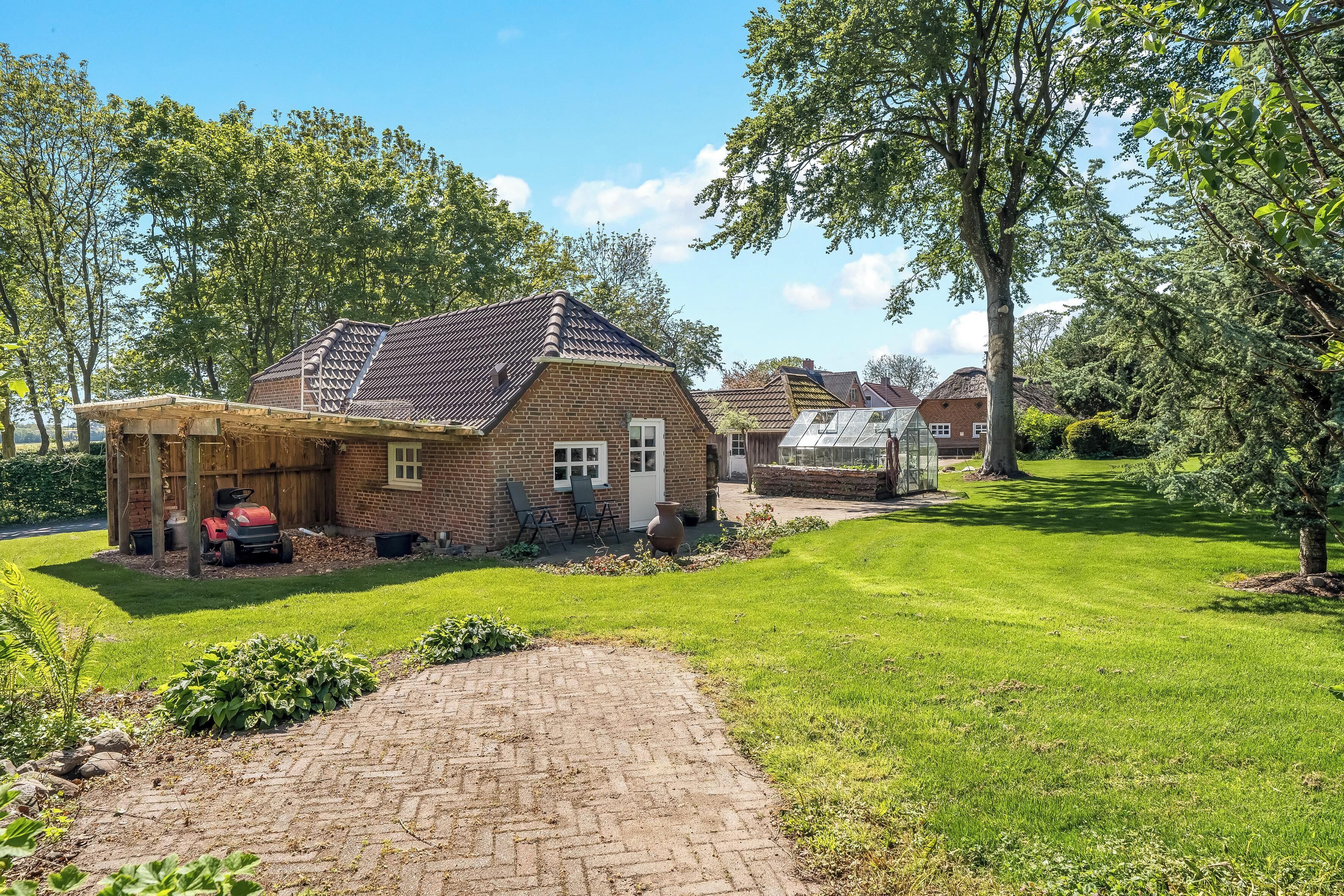 Une maison en briques avec une allée pavée, un patio couvert et une pelouse bien entretenue.