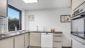 Una cucina moderna con lavastoviglie, lavello e finestra con tende.