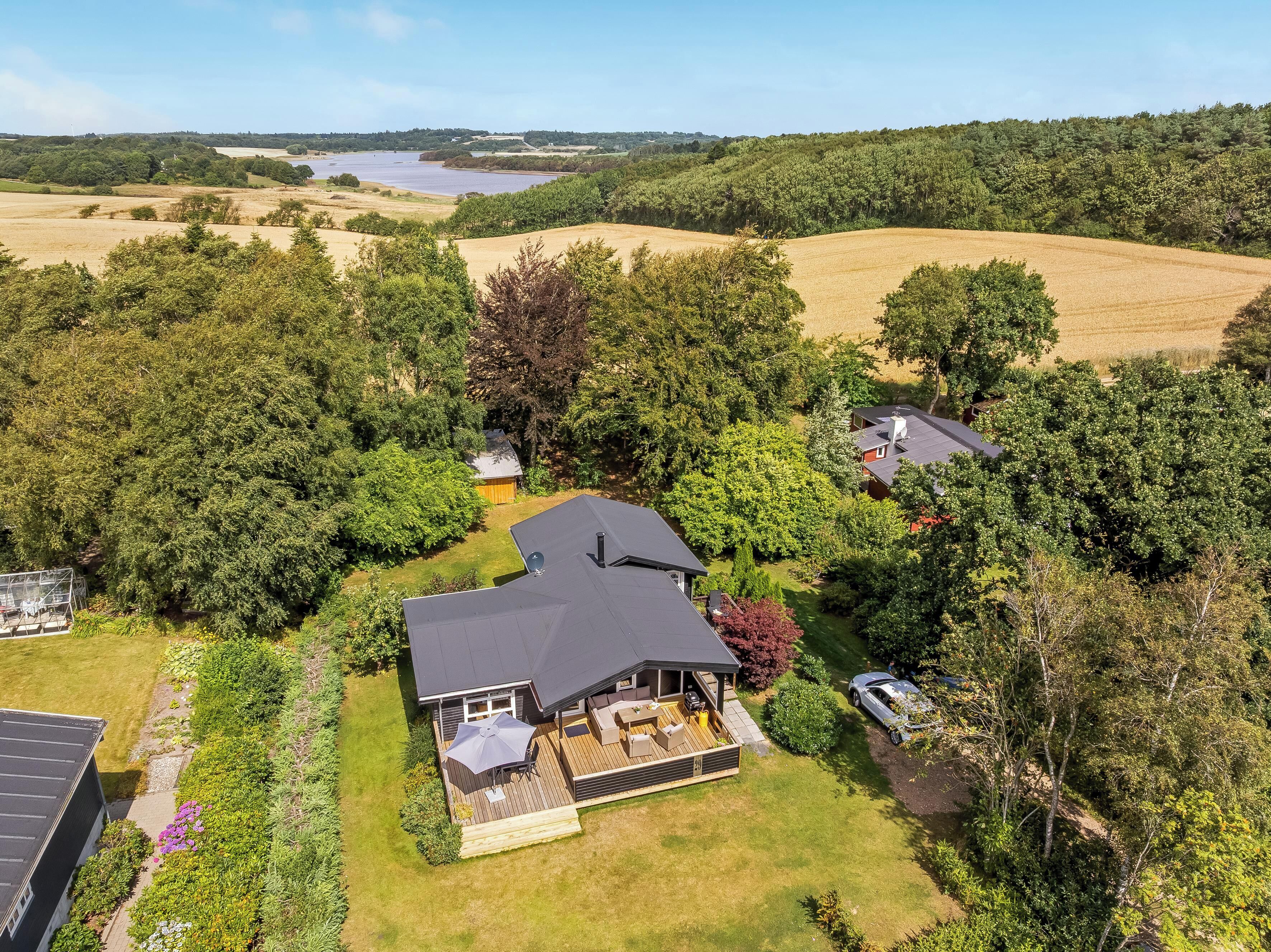 A residential property with a large deck, a swimming pool, and a view of a lake.