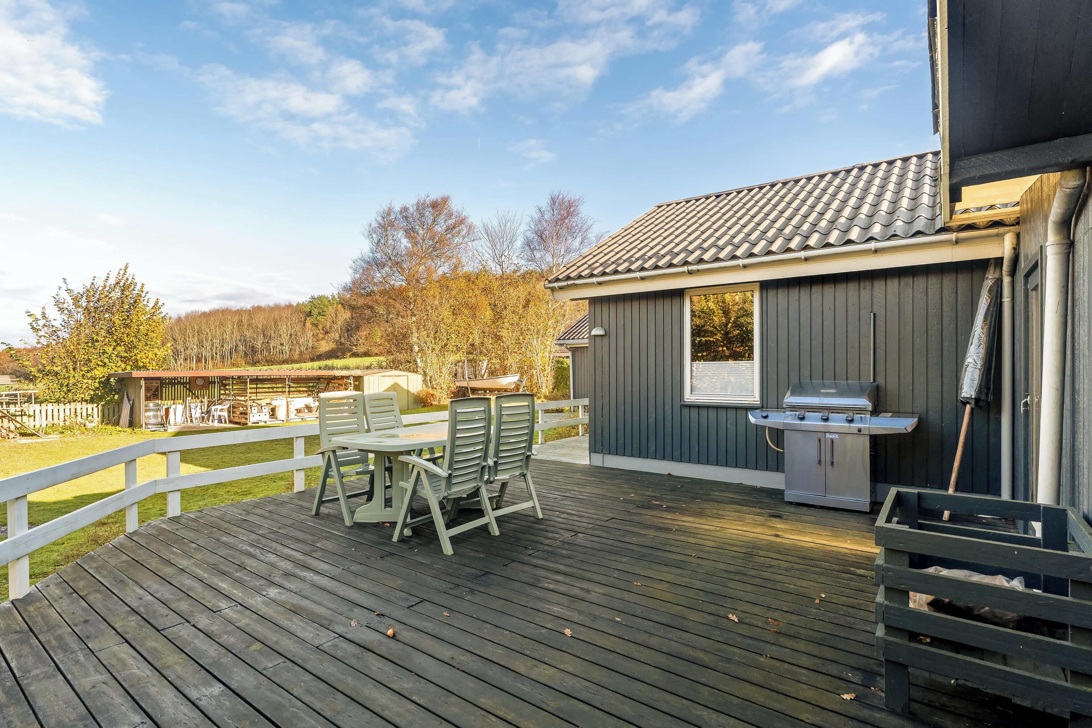 A deck with outdoor furniture, a grill, and a shed with a window.