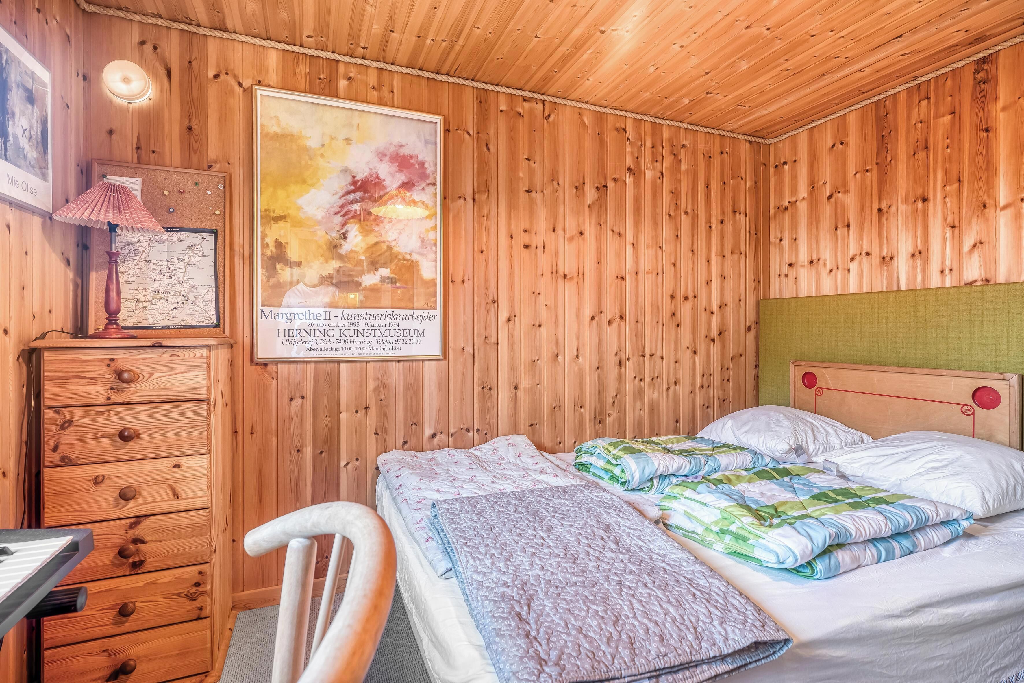 Una habitación con paneles de madera, una cama, un escritorio y una silla.