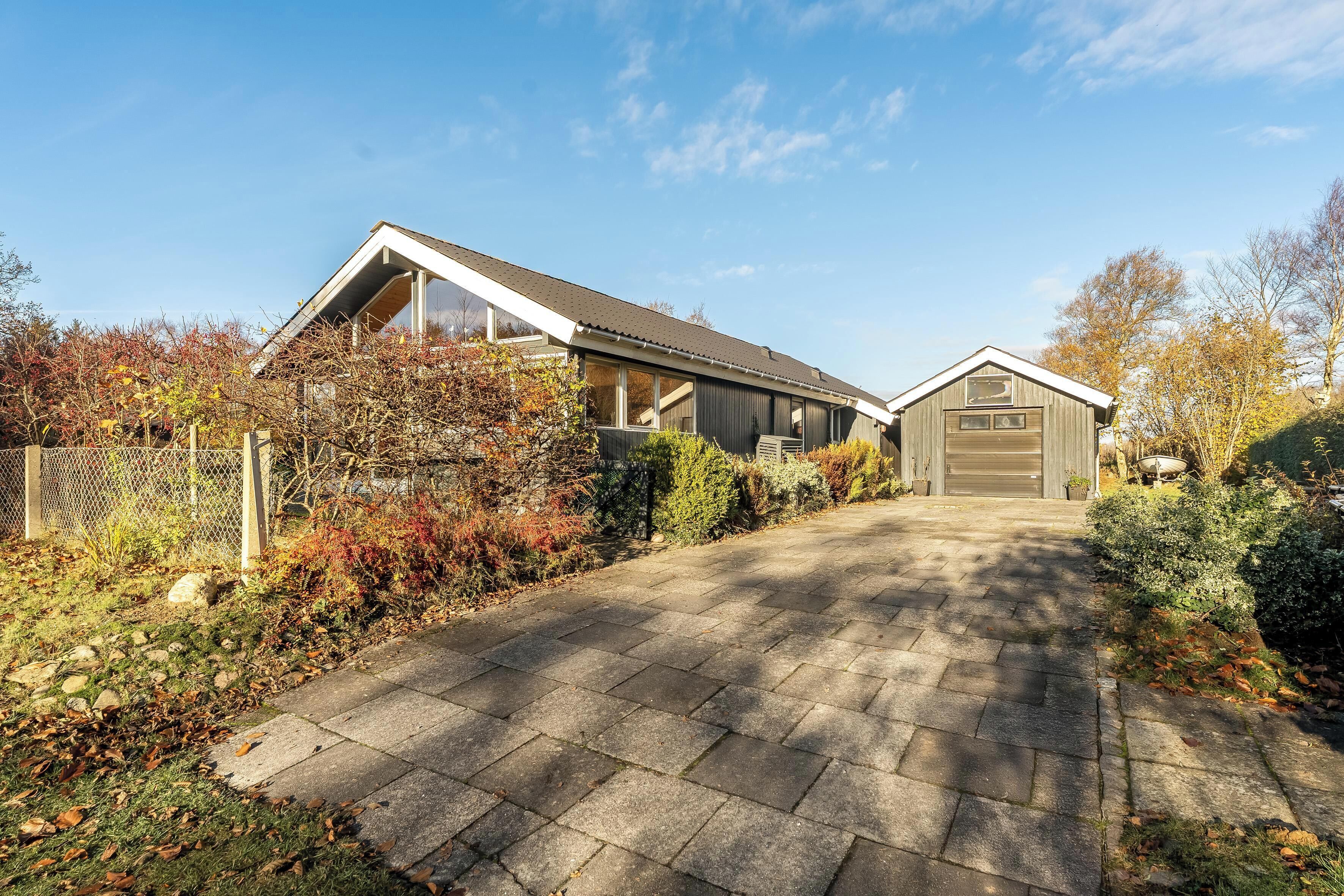 Een huis met twee verdiepingen en een geplaveid opritje dat naar een garage leidt.