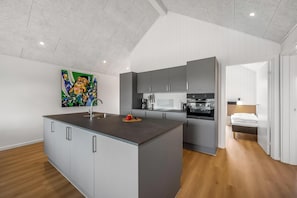 A modern kitchen with grey cabinets, a central island, and a painting on the wall. - Lovely holiday apartment from 2026 in Søndervig, close to the North Sea. (Ringkøbing)
