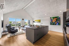 A modern kitchen with a central island, large windows, and a view of the outside. - Lovely holiday apartment from 2026 in Søndervig, close to the North Sea. (Ringkøbing)