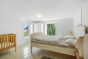 A bedroom with a bed, a crib, a window, and a lamp. - 18-person holiday home with views of the Fjord and lots of facilities. (Thyholm)