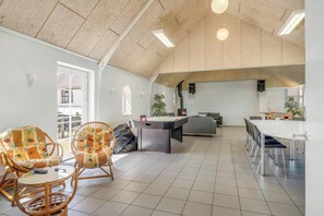 A spacious room with a high ceiling, a pool table, wicker chairs, a dining table with chairs, and a view of the outside. - 18-person holiday home with views of the Fjord and lots of facilities. (Thyholm)