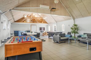A spacious living area with a foosball table, a sofa, a coffee table, and a staircase leading to an upper level. - 18-person holiday home with views of the Fjord and lots of facilities. (Thyholm)