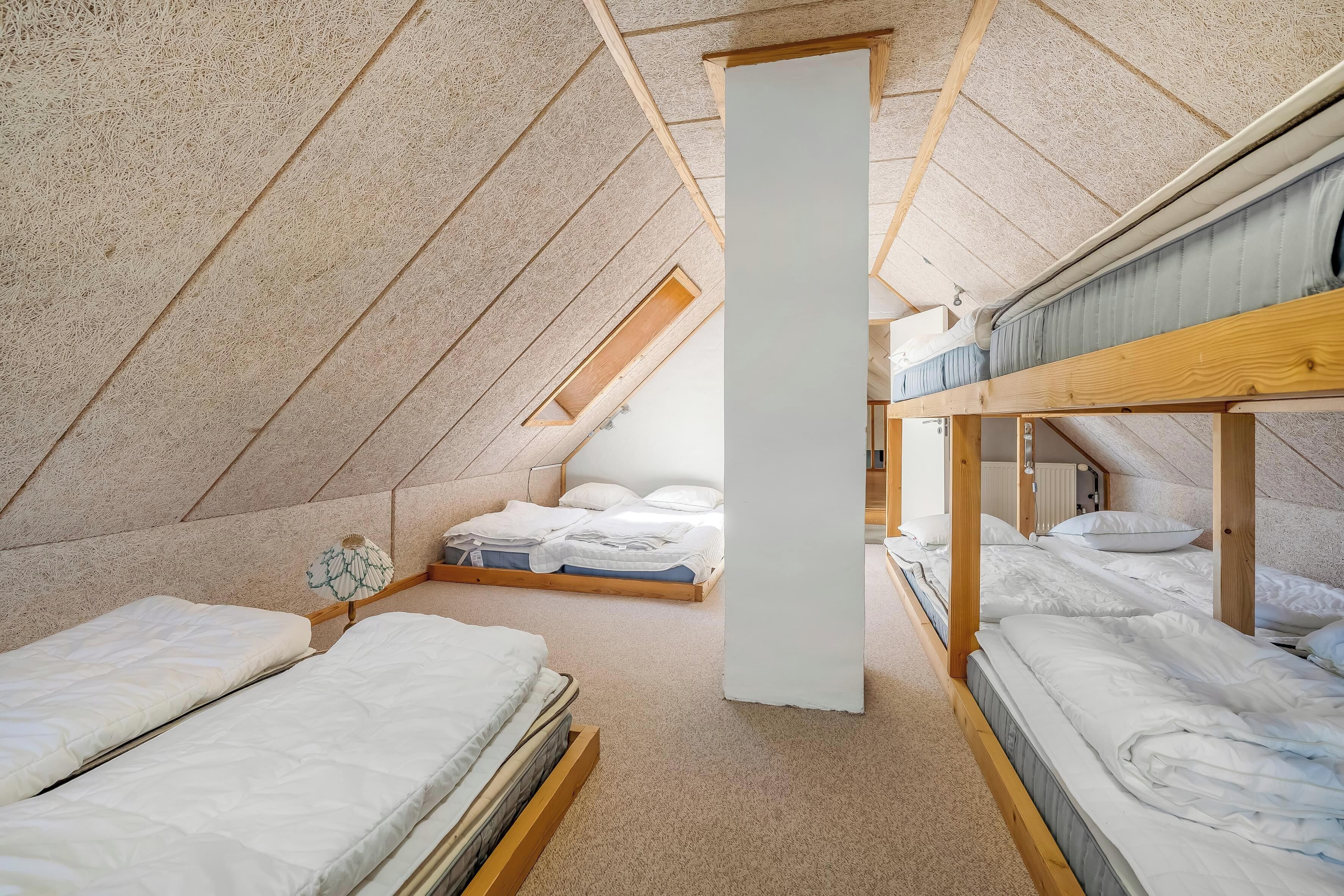 Una camera in stile dormitorio con letti a castello, un lucernario e un pilastro centrale.