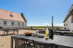 An outdoor patio with tables, chairs, and a bottle of water. - 18-person holiday home with views of the Fjord and lots of facilities. (Thyholm)