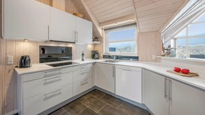 Moderni keittiö, jossa on valkoiset kaapit, suuri ikkuna ja näkymä ulos.