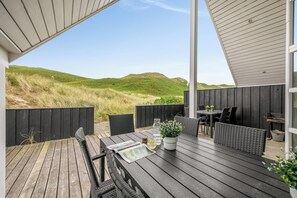 Eine Terrasse im Freien mit einem Holztisch, Stühlen und einem Blumentopf.