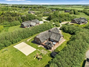 Une zone rurale avec des maisons aux toits de chaume, une aire de jeux et un court de tennis.