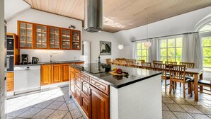 Una cucina moderna con mobili in legno, un'isola centrale e un'area pranzo con una grande finestra.