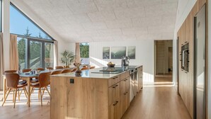 Eine moderne Küche mit einer zentralen Kochinsel, Holzschränken und einem Essbereich mit Stühlen und einem Tisch.