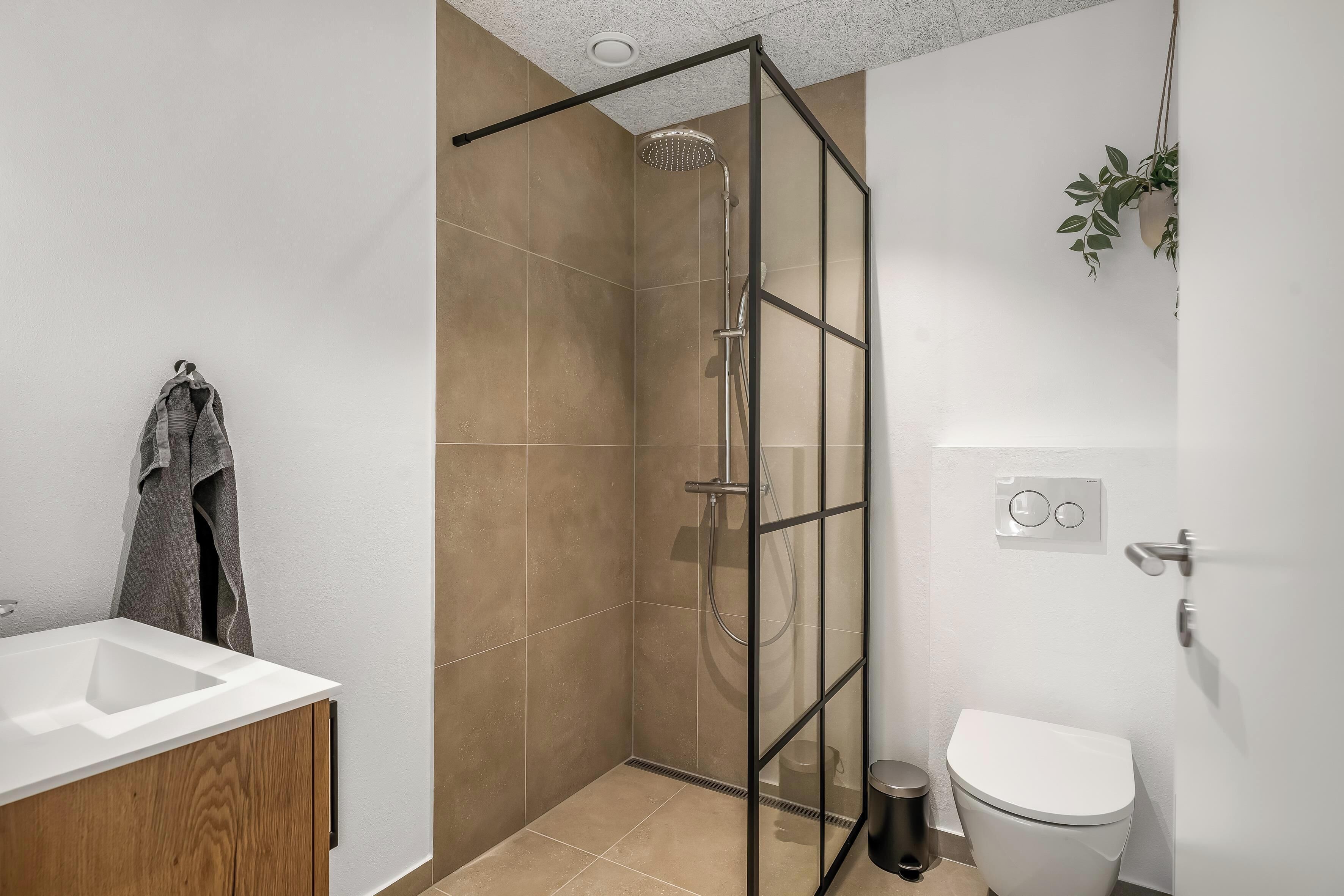 A modern bathroom with a shower enclosure, a toilet, and a sink.