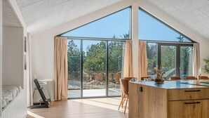 Ein geräumiges Zimmer mit einem großen Oberlicht, einem Holztisch und Blick ins Freie.