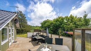 A wooden deck with outdoor furniture, a satellite dish, and a glass enclosure. - Well-maintained holiday home close to Ringkøbing Fjord. (Skjern)