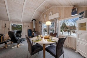 Puisesti sisustettu tila, jossa on pyöreä ruokapöytä, tuoleja, takka ja näkymä ikkunasta.