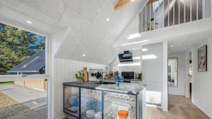 Eine moderne Küche mit einer Kücheninsel mit Glasfront, weißen Schränken und Blick ins Freie.