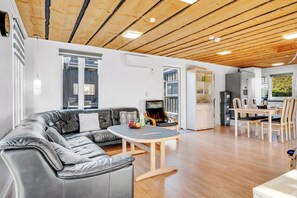 Ein modernes Wohnzimmer mit einer Ledersofa, einem Holzes Esstisch und einer Küchenzeile mit Schränken und Geräten.