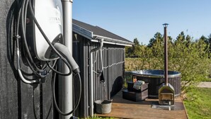 Eine JYSK-Ladestation für Elektrofahrzeuge, ein Whirlpool und ein Kaminofen in einem Hinterhof.