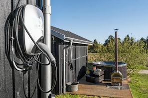 A JYSK electric vehicle charging station, a hot tub, and a wood-burning stove in a backyard setting. - 10-person holiday home with a wilderness bath and large terrace. (Hurup Thy)
