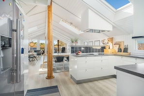 A modern kitchen with white cabinetry, a central island, and a skylight. - Renovated holiday home with 4 bedrooms 800 meters from the North Sea. (Thisted)