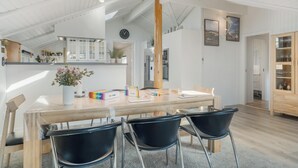 A spacious dining area with a wooden table, black chairs, and a vase of flowers. - Renovated holiday home with 4 bedrooms 800 meters from the North Sea. (Thisted)