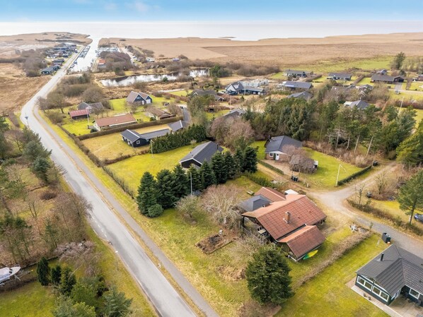 An aerial view of a residential area with houses, a road, and a body of water.