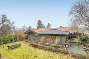 A house with a red-tiled roof, a wooden deck, and a small garden area.