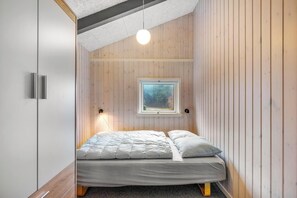 A bedroom with a bed, a window, and a pendant light.