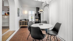 A modern interior with a round dining table, black chairs, a fireplace, and a skylight.